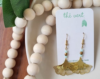 The Ginna Gold Ginkgo Leaf Earrings with faceted pale blue and gold glass beads
