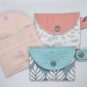 3 credit card wallets, one with keyring, one with snap strap. One is open to show the card slots and the snap closure from the inside.