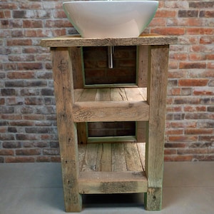 May include: A rustic wooden bathroom vanity with three shelves and a white porcelain sink. The vanity is made from reclaimed wood and has a natural, weathered finish.