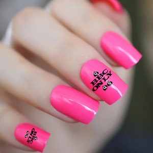 May include: Pink nail polish with black nail art that says "BBC ONLY" with a spade symbol on each side of the text.