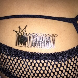 May include: Black Owned barcode tattoo with a crown and a spade symbol. The barcode reads 640509 046127.