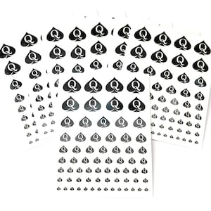 May include: Multiple sheets of white paper with black queen of spades symbols printed on them. The sheets are arranged in a stack.