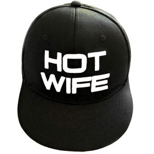 May include: Black baseball cap with a white embroidered design that says "HOT WIFE".