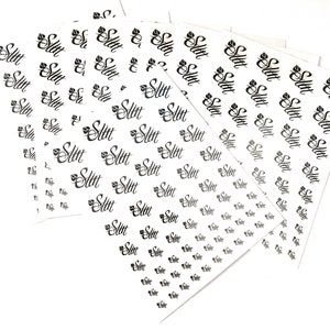 May include: Multiple sheets of white sticker paper with the word "Slit" printed in black cursive lettering.