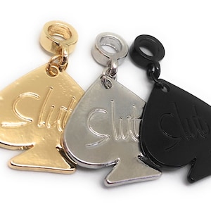 May include: Three charm pendants in gold, silver, and black, each shaped like a spade with the word "Slut" inscribed on it.