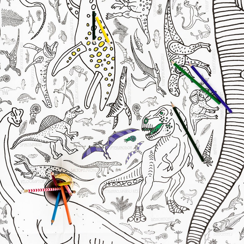 May include: A black and white coloring page featuring various dinosaurs, including a Tyrannosaurus Rex, a Spinosaurus, and a Pteranodon. The page is surrounded by colored pencils.