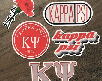 May include: A collection of stickers featuring the Greek letters and name "Kappa Psi". Designs include a red carnation, a pill-shaped sticker, a circular emblem with "1879", and a layered text design. The stickers are in red, white, and gray.