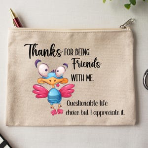 May include: Beige canvas zipper pouch with the text "Thanks for being Friends with me." A cartoon bird with pink wings and a blue body is in the center. The text "Questionable life choice but I appreciate it" is below the bird.