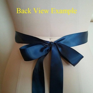 May include: Back view example of a navy blue satin ribbon tied in a bow around a waist.