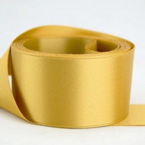 May include: A roll of gold satin ribbon. The ribbon is smooth and shiny.