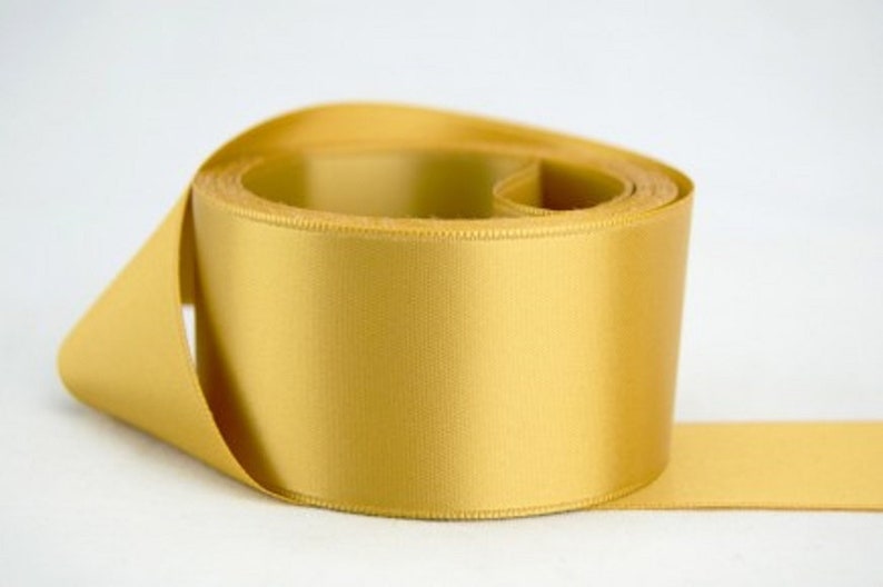 May include: A roll of gold satin ribbon. The ribbon is smooth and shiny.