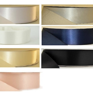 May include: Assortment of satin ribbon spools in various colors, including ivory, silver, navy blue, gold, and blush pink.