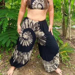 May include: Black and white tie-dye pants with a swirling pattern. The pants are loose fitting and have a wide leg.