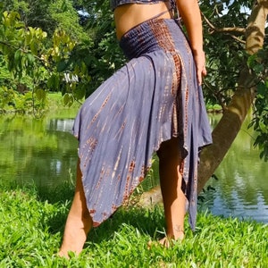 Puede incluir: Una falda de color gris y marrón con estampado tie-dye, cintura alta y vuelo asimétrico. La falda está hecha de una tela suave y ligera y tiene un estilo relajado y bohemio.