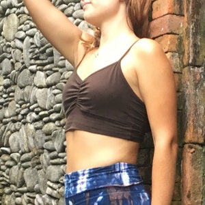May include: A brown cropped tank top with a gathered detail at the bust. The top is worn with a blue and white tie-dye print skirt.