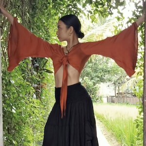 Top Lily con mangas acampanadas en color óxido de Lotus Tribe. Top bohemio cruzado, confeccionado con tejido de lyocell de pulpa de árbol sostenible y seda vegana. Top femenino, fluido y cruzado.