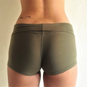 May include: Olive green athletic shorts with a high waist and a seam down the center back. The shorts are made of a soft, stretchy fabric.