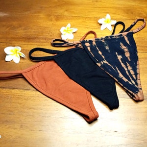 May include: Three pairs of underwear in different colors and patterns. One pair is black, one is rust colored, and one is tie-dye with black and white swirls.