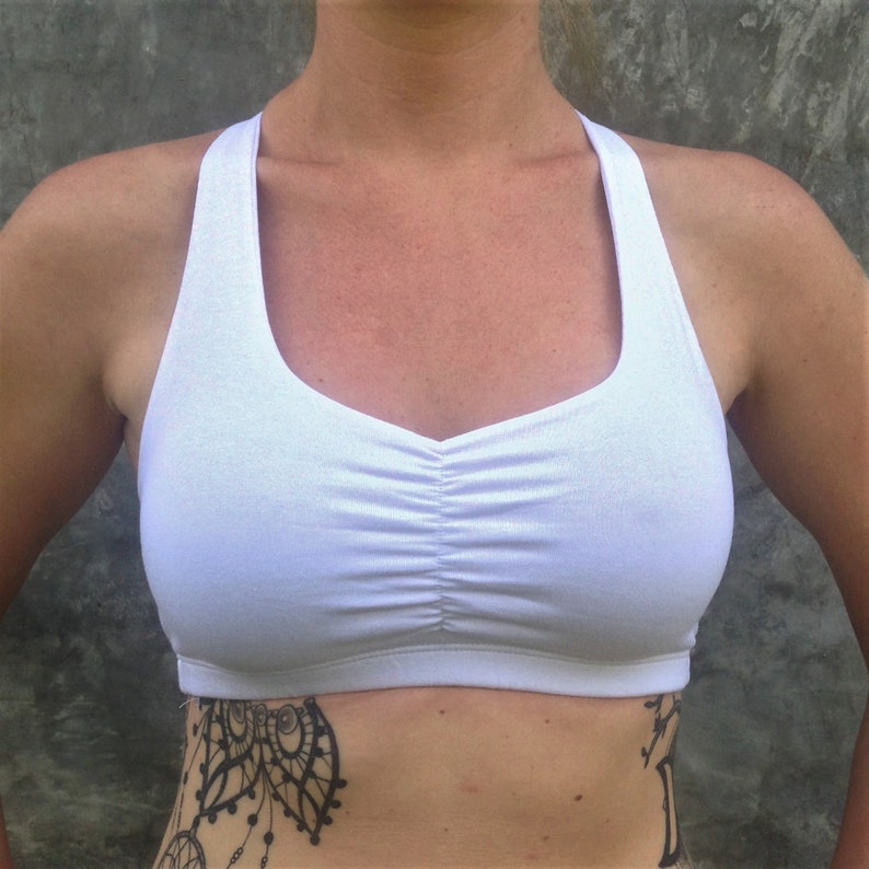 Pu&ograve; includere: Reggiseno sportivo bianco con schienale a sgancio rapido e un dettaglio arricciato sul davanti.