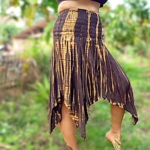 Puede incluir: Una falda de color marrón y amarillo con estampado tie-dye, cintura elástica y vuelo asimétrico.