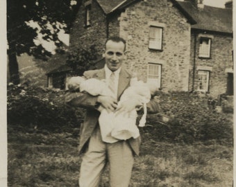 Man holding twin babies.  Vintage vernacular snapshot photograph of a proud father