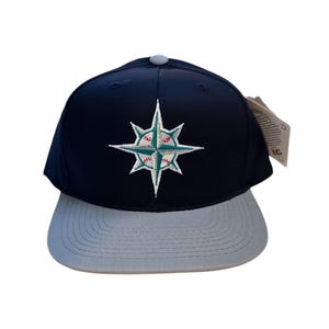 May include: A black and grey baseball cap with a green and white compass logo featuring a baseball in the centre. The logo is embroidered on the front of the cap.