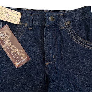 May include: A pair of dark blue denim jeans with a boot flare style. The jeans have a label that reads "Wrangler Boot Flare" and "No Fault 100% Cotton Denim with Sanforset".