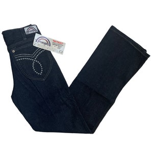 May include: A pair of dark blue denim jeans with a bootcut leg. The jeans have a Wrangler label on the back pocket and a white tag with the text "NO-FAULT 100% COTTON DENIM WITH STRETCH" on the front.
