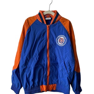 Könnte beinhalten: Eine blaue und orangefarbene Vintage-Baseballjacke der Detroit Tigers mit Reißverschluss und einem Tiger-Logo auf der Vorderseite. Die Jacke hat einen gerippten Kragen und Bündchen.