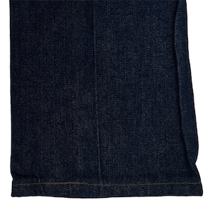 May include: Close-up of the bottom hem of a pair of dark blue denim jeans. The hem is sewn with a straight stitch and has a subtle brown thread.