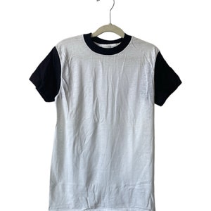 May include: A white t-shirt with black sleeves and a black ribbed crew neck.