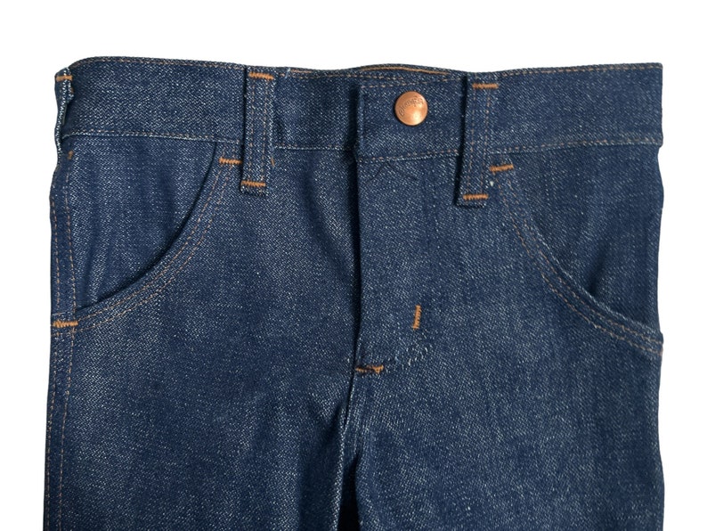 May include: A pair of blue denim jeans with a copper button and stitching detail.