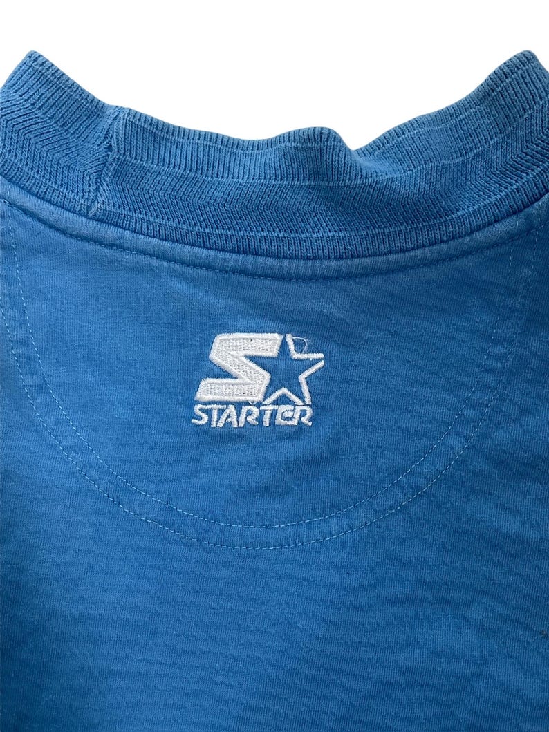 May include: A blue t-shirt with a white embroidered "Starter" logo on the back.