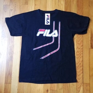 May include: Navy blue t-shirt with the Fila logo in white and red. The shirt has a tag attached at the neckline. The design includes white and red accent lines.