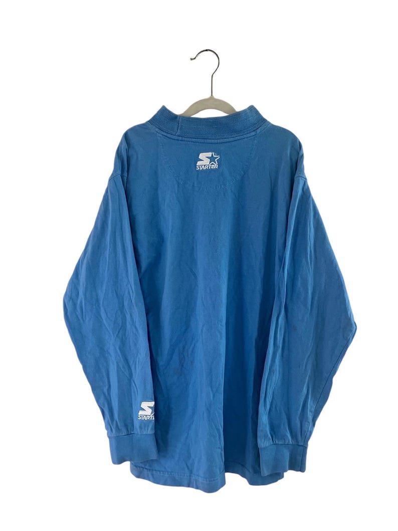 May include: A blue long-sleeved shirt with a white "Starter" logo on the back and a white "S" logo on the left sleeve.