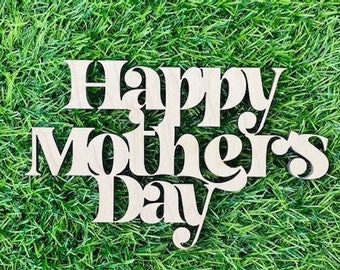 Könnte beinhalten: Ein helles Holzschild mit der Aufschrift "Happy Mothers Day" in einer dekorativen Schriftart. Das Schild befindet sich auf einem Hintergrund aus grünem Gras.