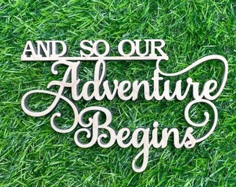 May include: Wooden sign with the text "And so our adventure begins" in a cursive font. The sign is on a green grass background.