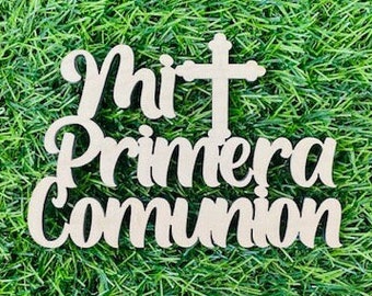 May include: Wooden cutout of the words "Mi Primera Comunión" in a cursive font with a cross above the words.