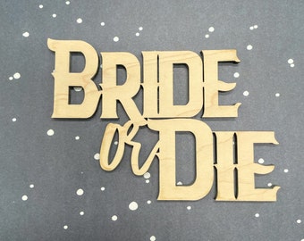 May include: Wooden sign with the text "Bride or Die" in a rustic font. The sign is light brown and has a distressed look.