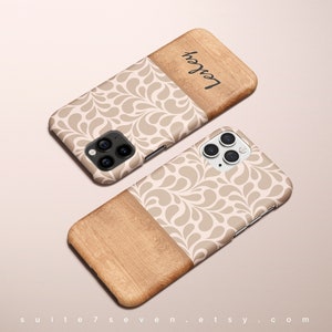Może przedstawiać: Beige i brązowe etui na telefon z wzorem drewna i białym wzorem kwiatowym. Etui ma wycięcie na obiektyw aparatu, a na plecach nadrukowany jest napis "Love".