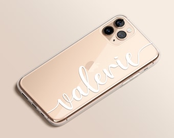 Può includere: Una custodia per telefono trasparente con un telefono dorato all'interno. La custodia ha il nome "Valerie" scritto in corsivo bianco.