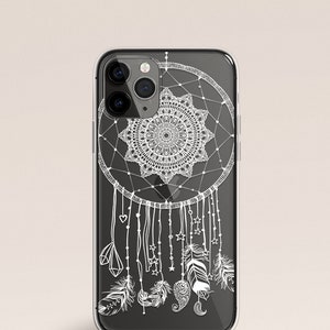 Puede incluir: Una funda transparente para teléfono con un diseño de atrapasueños blanco. El atrapasueños tiene un patrón de mandala circular en el centro y plumas que cuelgan de la parte inferior.