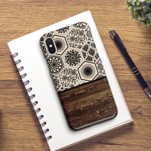 May include: A phone case with a black and white geometric pattern on the top half and a brown wood grain pattern on the bottom half.