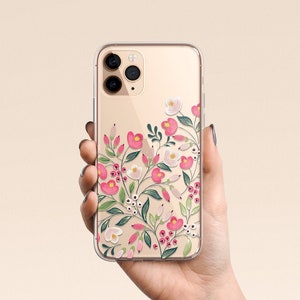 Puede incluir: Una funda transparente para tel&eacute;fono con un dise&ntilde;o floral. Las flores son rosas, blancas y verdes. La funda est&aacute; dise&ntilde;ada para un iPhone 11 Pro.