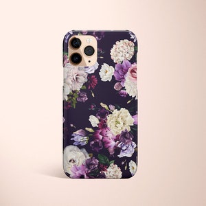 以下が含まれることがあります： 濃い色の背景に、紫、白、緑の花柄が描かれたiPhoneケース。ケースにはカメラの穴が開いており、iPhone用です。