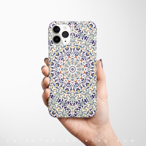 May include: A white iPhone case with a colorful mandala design. The design features blue, green, yellow, and orange colors.