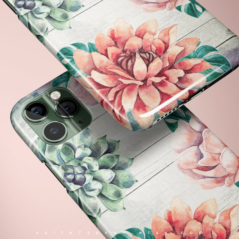 Pu&ograve; includere: Una custodia per telefono con uno sfondo in legno bianco e disegni floreali ad acquerello. I fiori sono rosa, rossi e verdi. La custodia ha un ritaglio per la fotocamera del telefono.