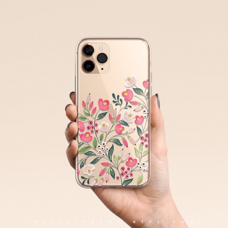 Puede incluir: Una funda transparente para tel&eacute;fono con un dise&ntilde;o floral. Las flores son rosas, blancas y verdes. La funda est&aacute; dise&ntilde;ada para un iPhone 11 Pro.