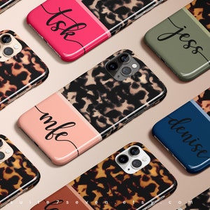 May include: A set of eight personalized phone cases with a tortoiseshell pattern and a contrasting color stripe. The names "Jess", "Denise", "Mbe", "Tsk" are visible on the cases.