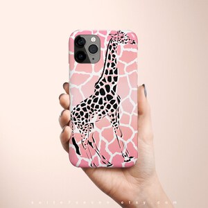 May include: A pink and white iPhone case with a black and white giraffe silhouette. The giraffe is standing on a pink and white giraffe print background.